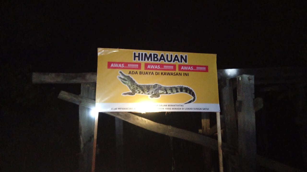 Relawan Peduli Kemanusiaan Satui memasang spanduk imbauan waspada buaya di sepanjang bantaran Sungai Satui, Kabupaten Tanah Bumbu, Sabtu (24/5/2025).