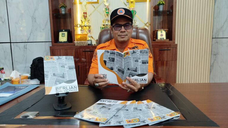 Rahmi, Kepala Pelaksana BPBD Balangan, memegang buku Berlian sebagai dokumentasi tiga tahun penanganan bencana. (Dok. BPBD Balangan)