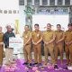 Kepala BPJS Ketenagakerjaan Batulicin dan Kepala Dinas PMD Tanah Bumbu menyerahkan simbolis manfaat jaminan sosial ketenagakerjaan kepada ahli waris pekerja desa, Senin (14/7/2025).