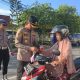 Wakapolres Kotabaru Kompol Andi Ahmad Bustanil membagikan bendera Merah Putih kepada warga di Simpang Empat Pasar Kemakmuran, Jumat (8/8/2025).