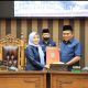 Wakil Ketua I DPRD Tanah Bumbu H. Hasanuddin menyerahkan dokumen Raperda kepada Sekda Yulian Herawati sebagai perwakilan Bupati dalam Rapat Paripurna, Senin (8/9/2025).