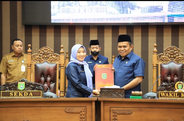 Wakil Ketua I DPRD Tanah Bumbu H. Hasanuddin menyerahkan dokumen Raperda kepada Sekda Yulian Herawati sebagai perwakilan Bupati dalam Rapat Paripurna, Senin (8/9/2025).