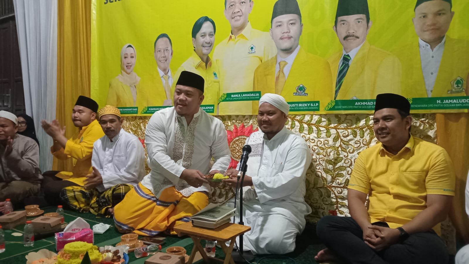 Ketua DPD Partai Golkar Kota Banjarbaru Gusti Rizky Sukma Iskandar Putera menyerahkan potongan tumpeng kepada Tuan Guru Syaifullah saat peringatan HUT ke-61 Partai Golkar di Majelis Alfatih Wali Imdad, Banjarbaru.