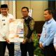 Bupati Tanah Laut H. Rahmat Trianto menyerahkan pamflet kampanye anti korupsi kepada Ketua DPRD H. Khairil Anwar sebagai simbol komitmen bersama mewujudkan pemerintahan yang bersih dan berintegritas.