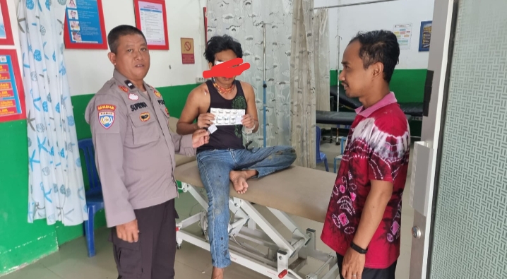 Petugas kepolisian mengawal pria terduga pelaku pencurian motor yang mengalami luka akibat diamuk massa saat dibawa ke Puskesmas Sebamban 1 untuk mendapat perawatan.