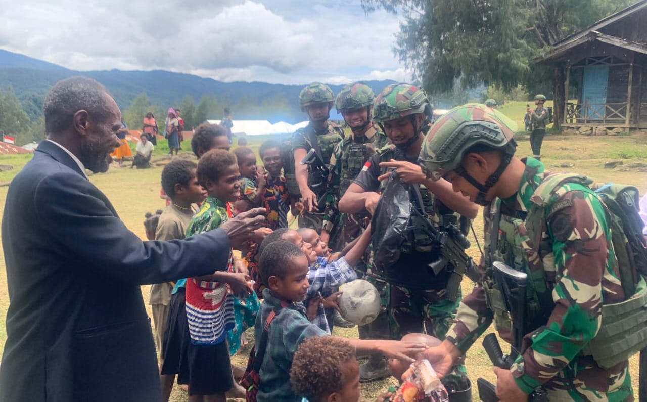 Personel Satgas Yonif 113/JS membagikan biskuit dan permen kepada anak-anak Kampung Pogapa sebagai bentuk kepedulian dan upaya menumbuhkan semangat kebersamaan.
