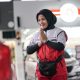 Petugas SPBU Pertamina tersenyum menyapa pengendara mobil dengan ramah saat melayani pengisian BBM.