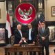 Perwakilan Pertamina Patra Niaga dan perusahaan energi global berjabat tangan usai penandatanganan kerja sama energi di Washington DC dengan latar lambang Garuda Indonesia.