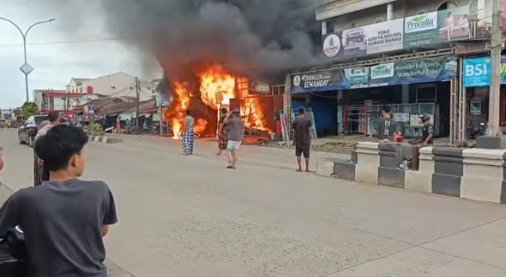 Kebakaran ruko pom mini di Satui Tanah Bumbu dengan api besar dan asap hitam saat proses pemadaman oleh Damkar dan relawan.