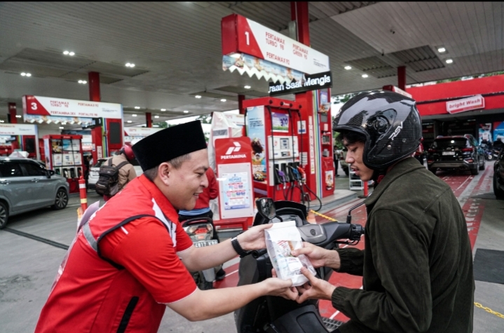 Petugas SPBU Pertamina memberikan paket takjil kepada pengendara motor saat program berbagi takjil Ramadan di area SPBU