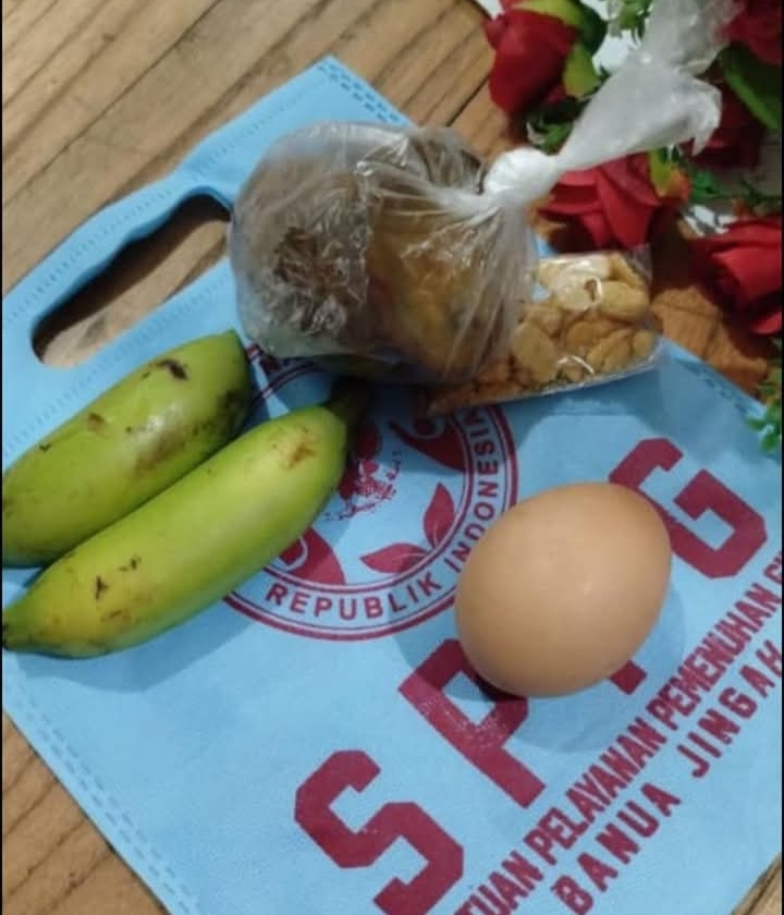 Paket menu Program Makan Bergizi Gratis berisi nasi, telur, pisang, dan lauk sederhana di atas alas bertuliskan SPPG.