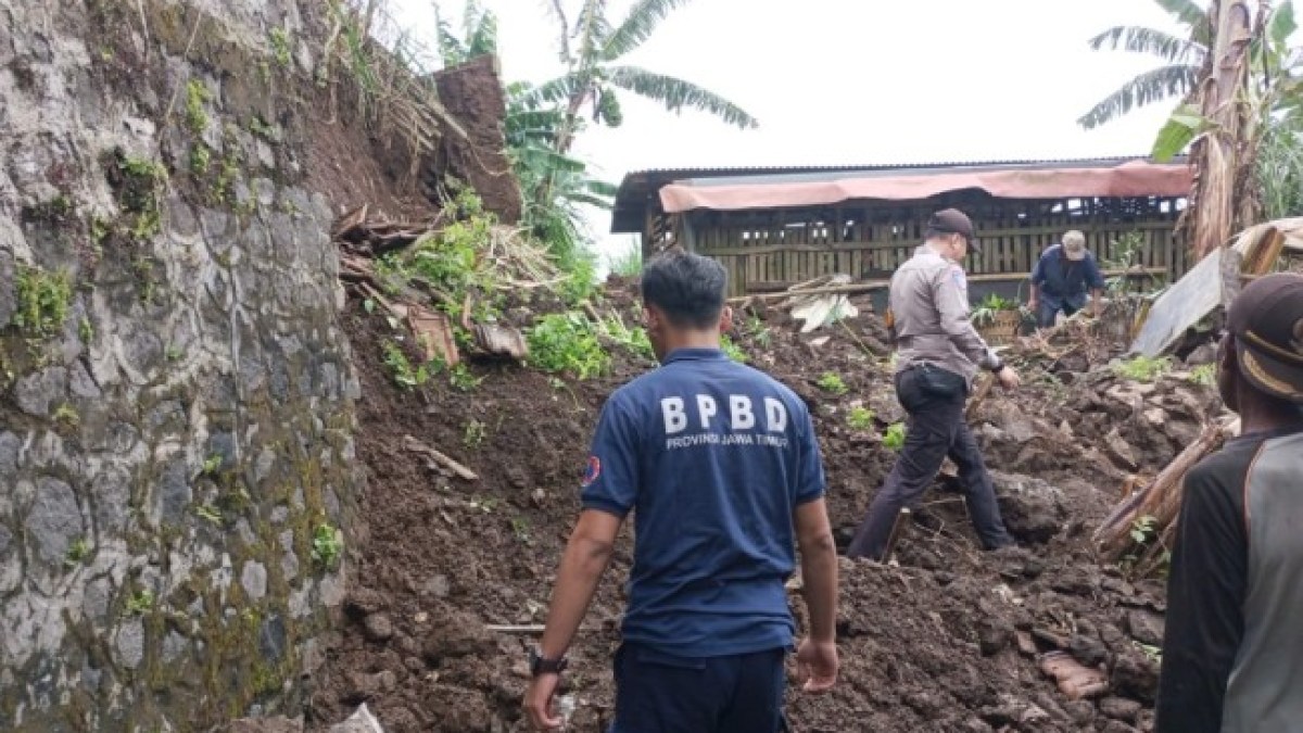 Petugas BPBD dan warga membersihkan material longsor dari tebing setinggi tujuh meter yang menutup akses jalan di Lawang, Kabupaten Malang.