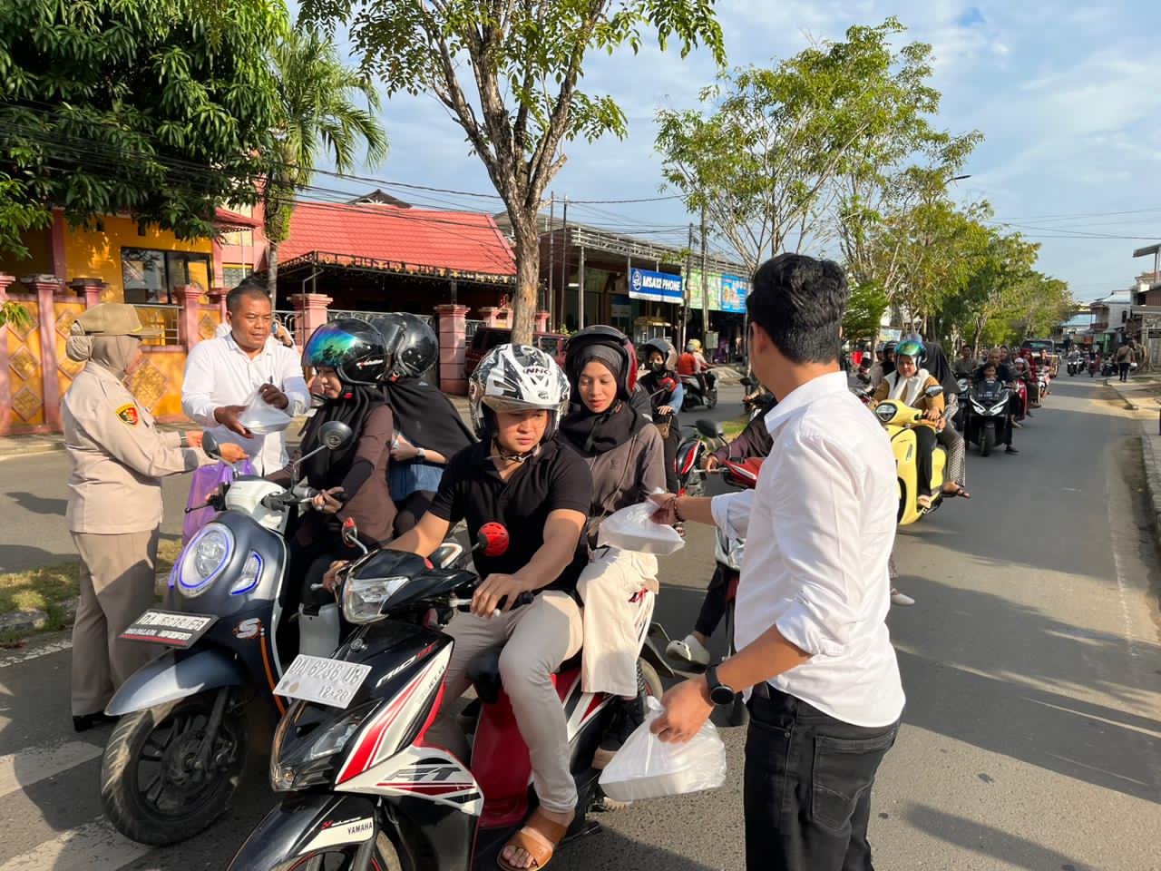 Anggota Satreskrim Polres HSU membagikan paket takjil kepada pengendara motor di Jalan Tembus Paliwara Amuntai saat bulan Ramadan.