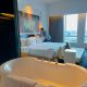 Kamar hotel ARTOTEL TS Suites Surabaya dengan desain luas, dilengkapi bathtub, tempat tidur besar, dan pemandangan kota untuk staycation Lebaran.