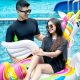 Pria dan wanita bersantai di kolam renang menggunakan pelampung unicorn warna-warni, menikmati suasana liburan di area waterpark.