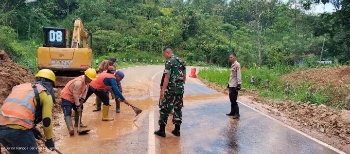 Petugas TNI, Polri dan pekerja membersihkan material longsor di jalan lingkar Waduk Jatigede menggunakan alat berat.