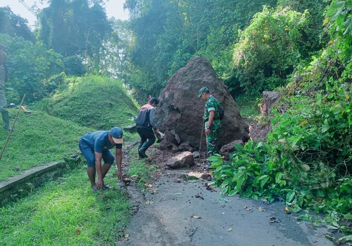 Petugas TNI dan warga membersihkan batu besar akibat longsor yang menutup jalan desa di Jatigede Sumedang.