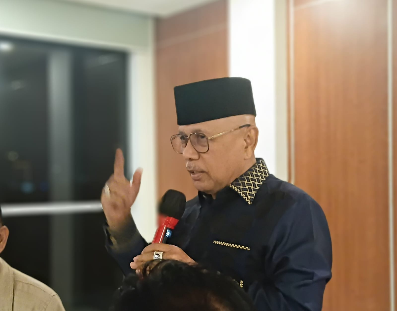 Darmizal memberikan pernyataan soal video Saiful Mujani sambil berbicara menggunakan mikrofon di dalam ruangan.