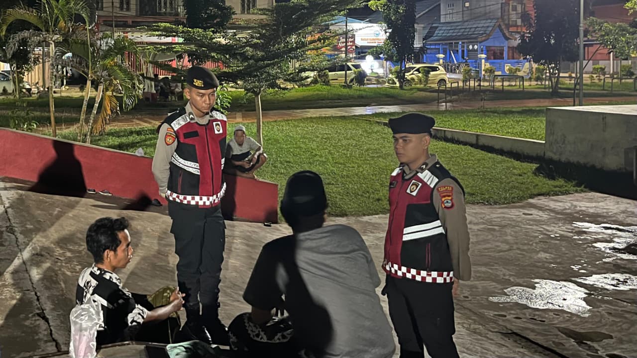Petugas polisi melakukan patroli dan dialog dengan warga di ruang terbuka publik Tanah Laut pada malam hari.