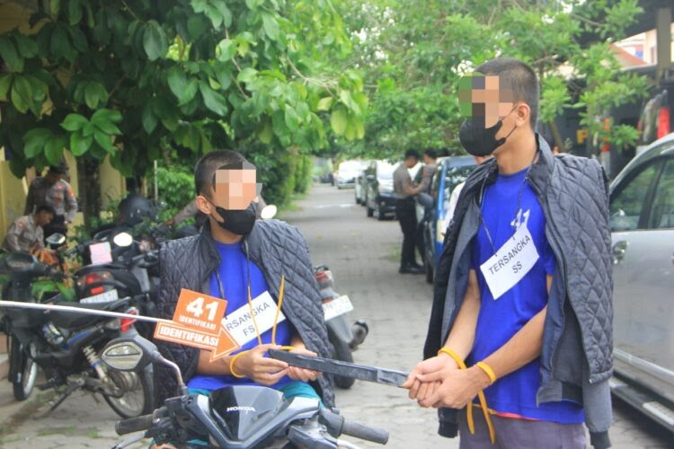 Tersangka memperagakan rekonstruksi pembunuhan di Bantul dengan barang bukti senjata tajam di lokasi kejadian.