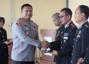 Kapolres Tanah Bumbu AKBP Arief Prasetya berjabat tangan dengan personel purna bhakti saat penyerahan penghargaan di acara wisuda.