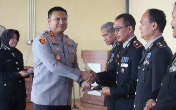 Kapolres Tanah Bumbu AKBP Arief Prasetya berjabat tangan dengan personel purna bhakti saat penyerahan penghargaan di acara wisuda.