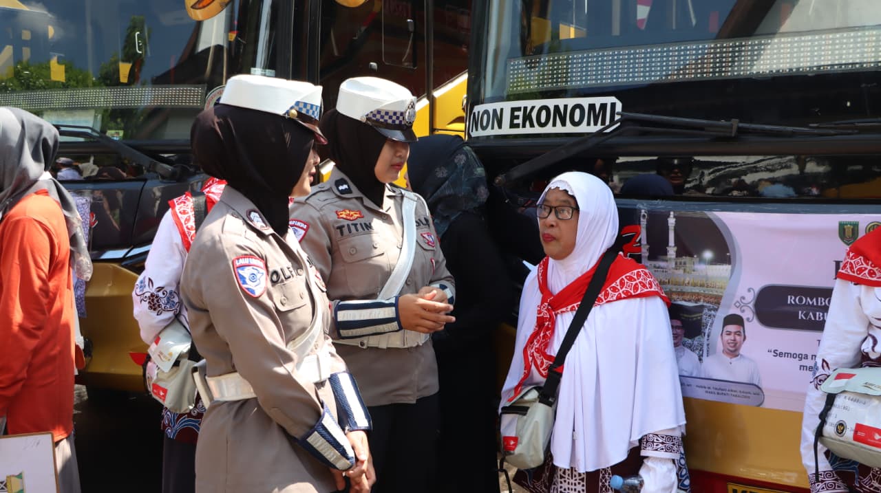 petugas polisi membantu calon jemaah haji naik bus sebelum keberangkatan di Tabalong