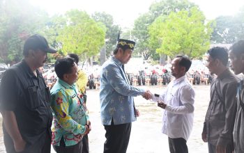 Wakil Bupati Pulang Pisau berjabat tangan dengan petani saat penyerahan bantuan hand tractor di halaman kantor dinas pertanian.