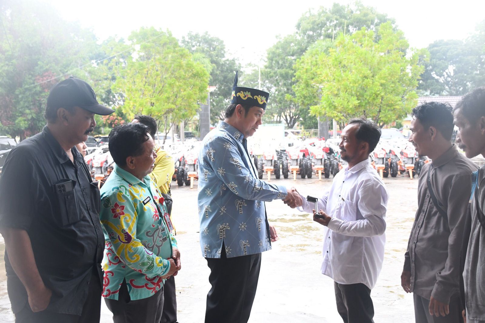 Wakil Bupati Pulang Pisau berjabat tangan dengan petani saat penyerahan bantuan hand tractor di halaman kantor dinas pertanian.