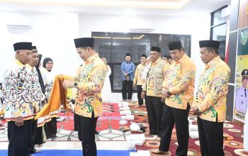 Bupati Pulang Pisau menyerahkan perlengkapan kepada jemaah haji dalam acara pelepasan keberangkatan haji tahun 2026 di dalam ruangan.
