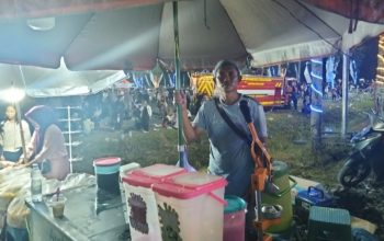 Pedagang kaki lima menjual es jus dan es kelapa muda di acara Aksi Inovasi Tanah Bumbu 2026 dengan banyak pengunjung.
