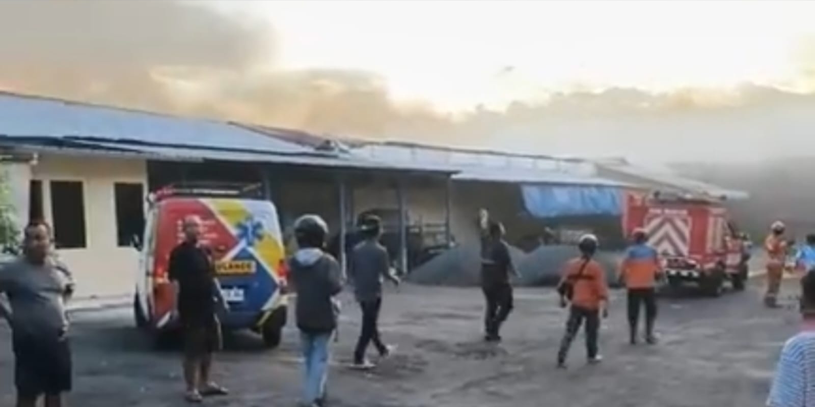 Petugas damkar dan warga di lokasi kebakaran gudang pabrik rokok di Buring Malang dengan asap tebal membumbung dari bangunan.