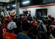 Proses evakuasi penumpang KRL di Stasiun Bekasi Timur setelah tabrakan dengan kereta jarak jauh, dengan petugas dan warga membantu di peron.