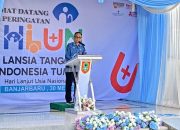 Pria berdiri di belakang podium, latar belakang spanduk HLUN ke-30