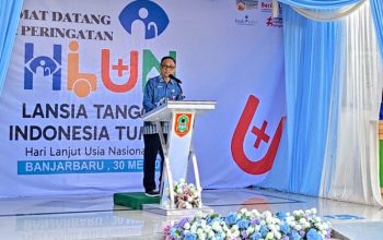 Pria berdiri di belakang podium, latar belakang spanduk HLUN ke-30