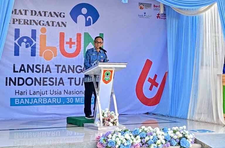 Pria berdiri di belakang podium, latar belakang spanduk HLUN ke-30