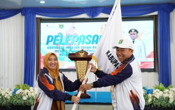 Sekda Tanah Bumbu menyerahkan bendera kontingen atlet pelajar saat pelepasan menuju POPDA Kalsel 2026 di Batulicin.
