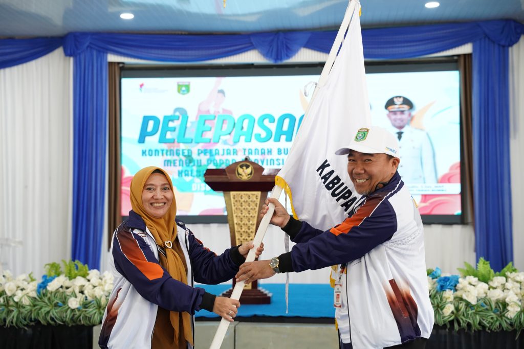 Sekda Tanah Bumbu menyerahkan bendera kontingen atlet pelajar saat pelepasan menuju POPDA Kalsel 2026 di Batulicin.
