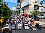 Ribuan buruh berkonvoi menggunakan kendaraan dan membawa spanduk saat aksi Hari Buruh Internasional 2026 di Surabaya.