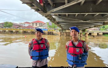 Dua anggota polisi perairan berjaga di Sungai Nagara Amuntai di bawah jembatan saat pengamanan balap jukung HSU