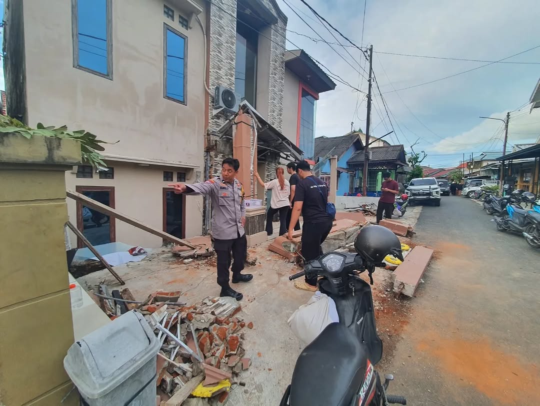 Polisi dan warga memeriksa lokasi rumah amblas di Banjarmasin Utara dengan puing bangunan terlihat di depan rumah.