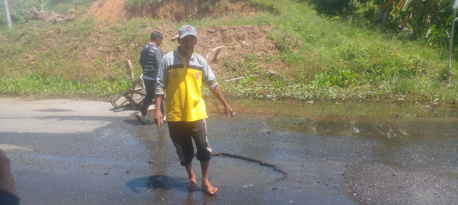 Warga memperlihatkan jalan berlubang dan tergenang air di Pal 6 Desa Sigam, Kotabaru.