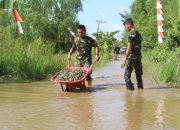 Anggota Kodim 1009/Tanah Laut memperbaiki jalan rusak dan tergenang air di Desa Handil Labuan Amas untuk mendukung distribusi material jembatan.