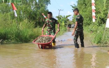 Anggota Kodim 1009/Tanah Laut memperbaiki jalan rusak dan tergenang air di Desa Handil Labuan Amas untuk mendukung distribusi material jembatan.