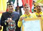Papan penghargaan desa percontohan anti korupsi untuk Desa Talio Muara.