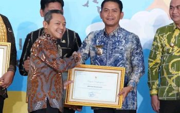 Wali Kota Banjarmasin memegang piagam penghargaan revitalisasi bahasa daerah di atas panggung.
