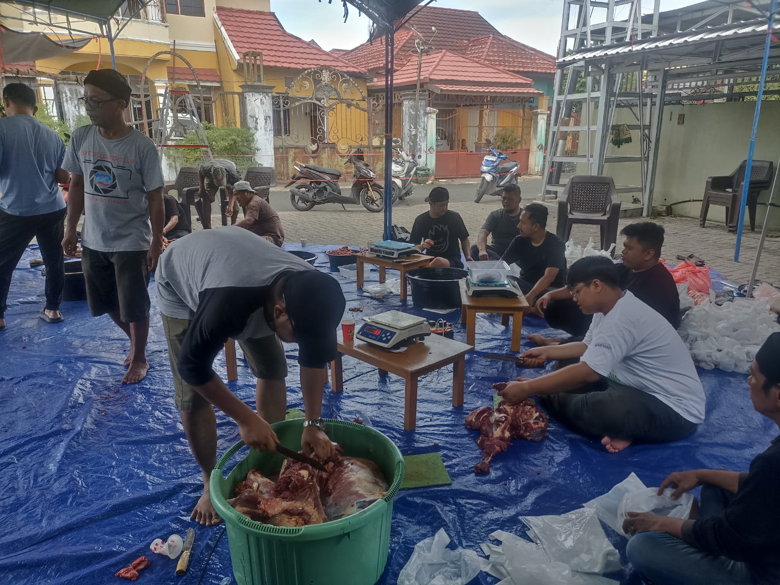 Warga bergotong royong memotong daging kurban di halaman Masjid Ar Raudhah.