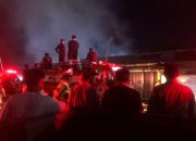 Petugas damkar menyemprotkan air ke bangunan kontrakan yang terbakar.