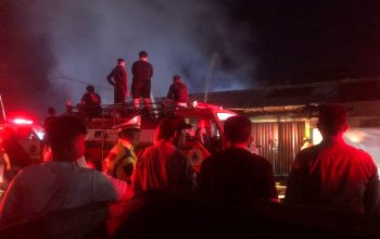 Petugas damkar menyemprotkan air ke bangunan kontrakan yang terbakar.