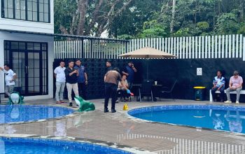 Polisi berseragam mengukur kedalaman kolam renang dengan alat ukur